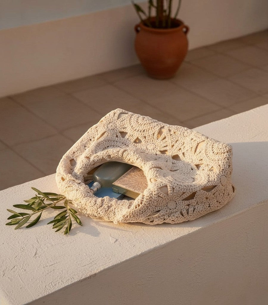 Bolso de rejilla Clarvyna color crema con diseño de crochet calado sobre un muro exterior al atardecer