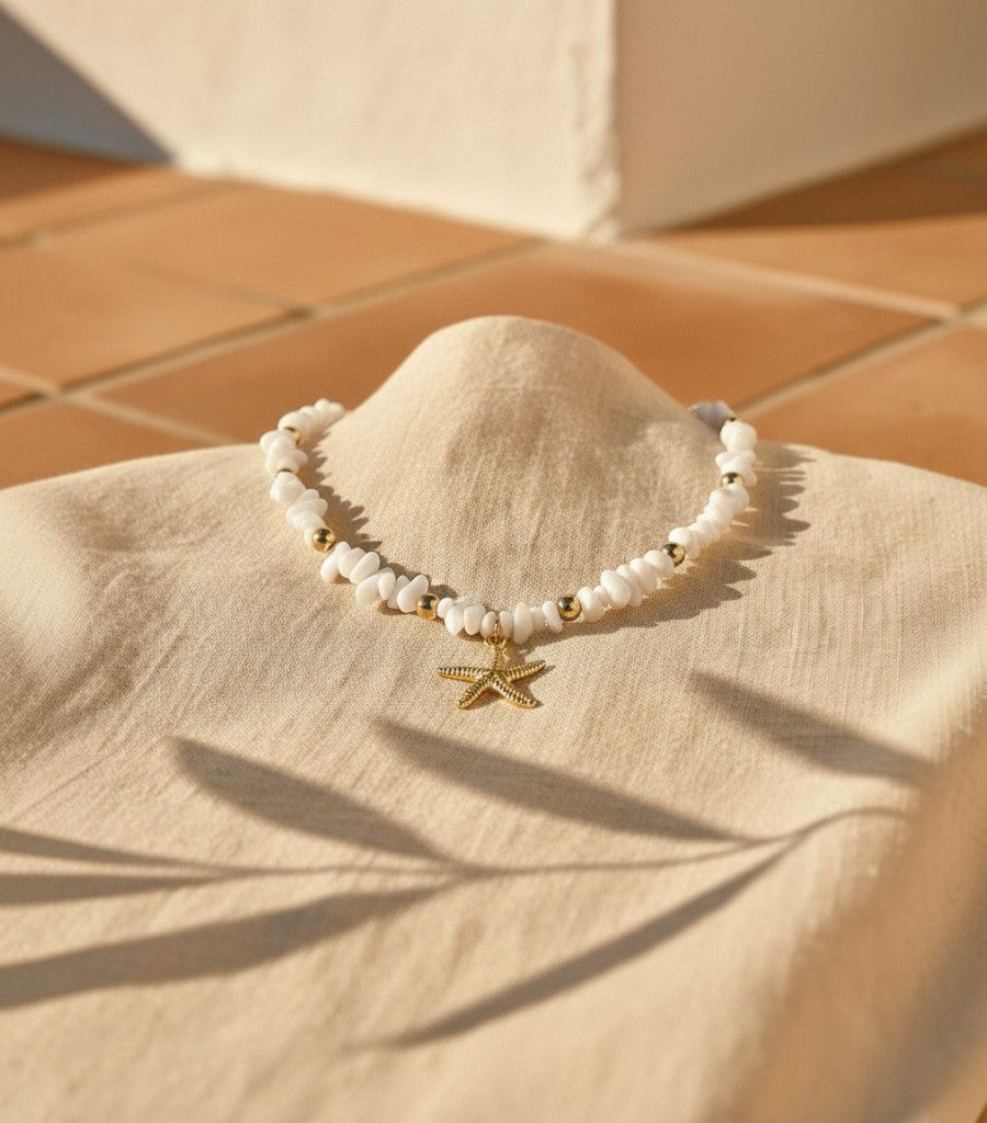 Collar Clarvyna con piedras naturales blancas, cuentas doradas y colgante de estrella de mar artesanal.