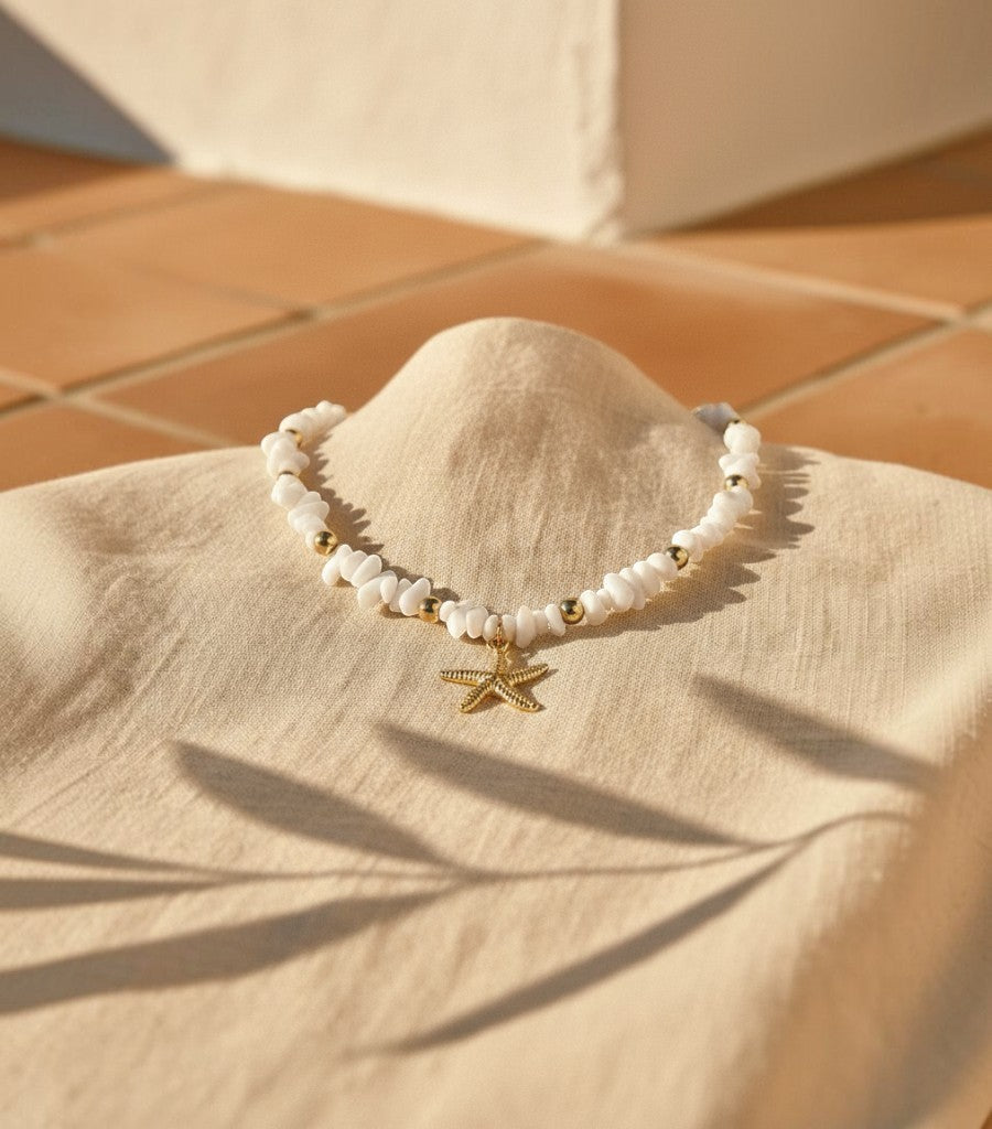 Collar Clarvyna con piedras naturales blancas, cuentas doradas y colgante de estrella de mar artesanal.