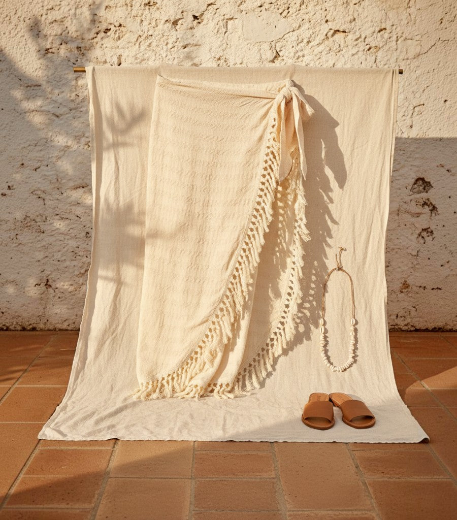 Falda pareo cruzada Clarvyna en color crema con flecos, ideal para looks de verano en la playa o cenas costeras.
