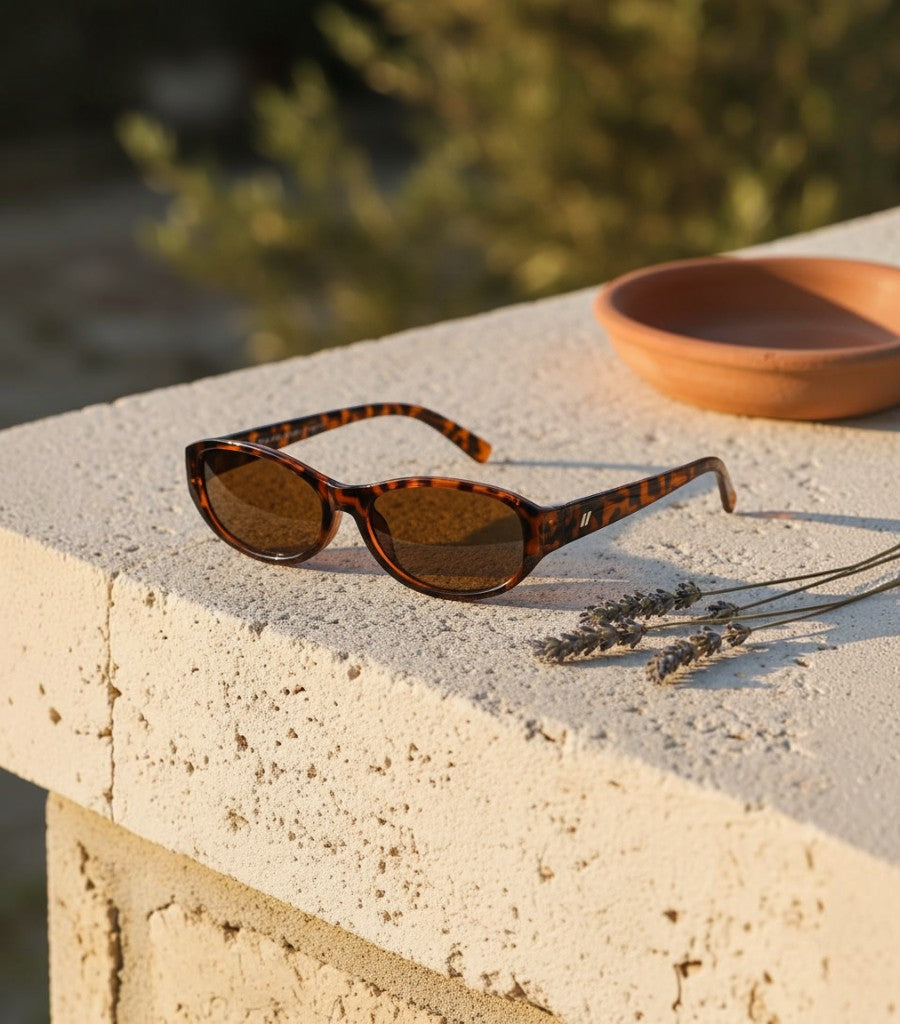 Gafas de sol Clarvyna con montura ovalada estilo carey retro sobre una superficie de piedra con lavanda