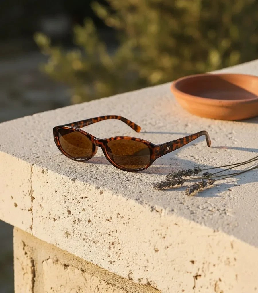 Gafas de sol Clarvyna con montura ovalada estilo carey y cristales marrones sobre una superficie de piedra