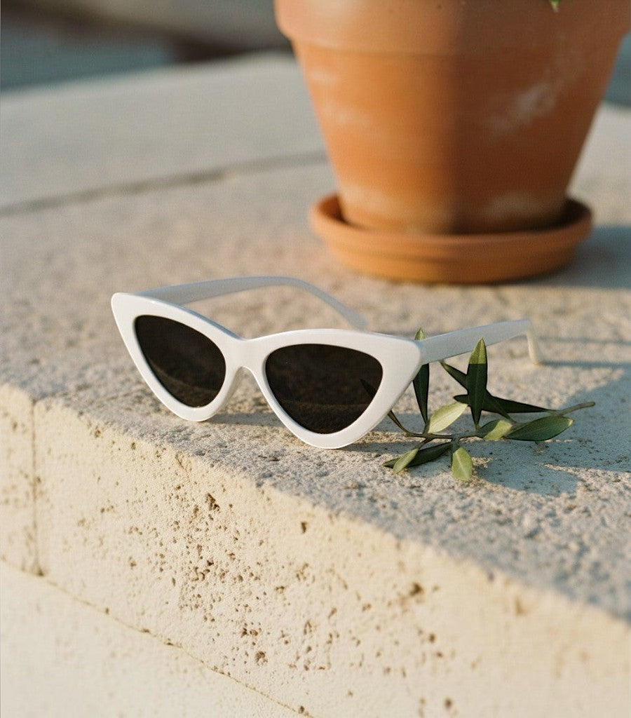 Gafas de sol Clarvyna modelo Cat Eye Walker con montura blanca y cristales oscuros sobre una superficie de piedra