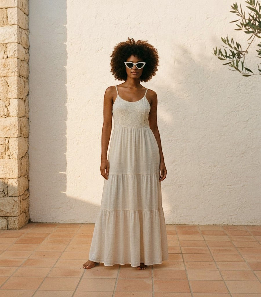 Mujer con gafas de sol Clarvyna Cat Eye Walker blancas y vestido largo beige en una terraza soleada