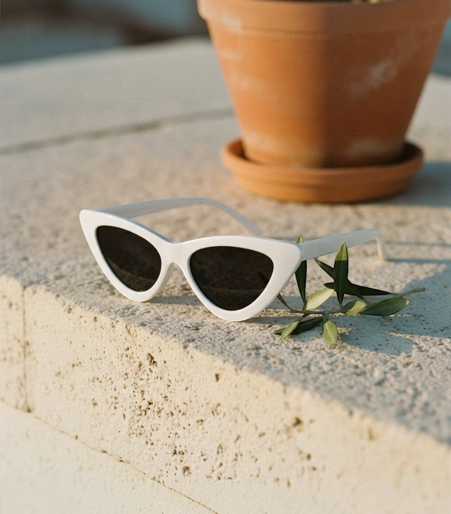 Gafas de sol Clarvyna modelo Cat Eye Walker con montura blanca y cristales oscuros sobre una superficie de piedra