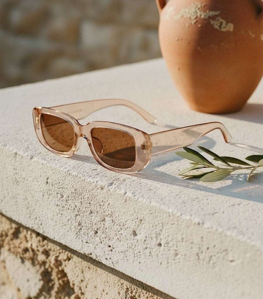 Gafas de sol cuadradas Clarvyna con montura transparente y cristales marrones sobre una superficie de piedra