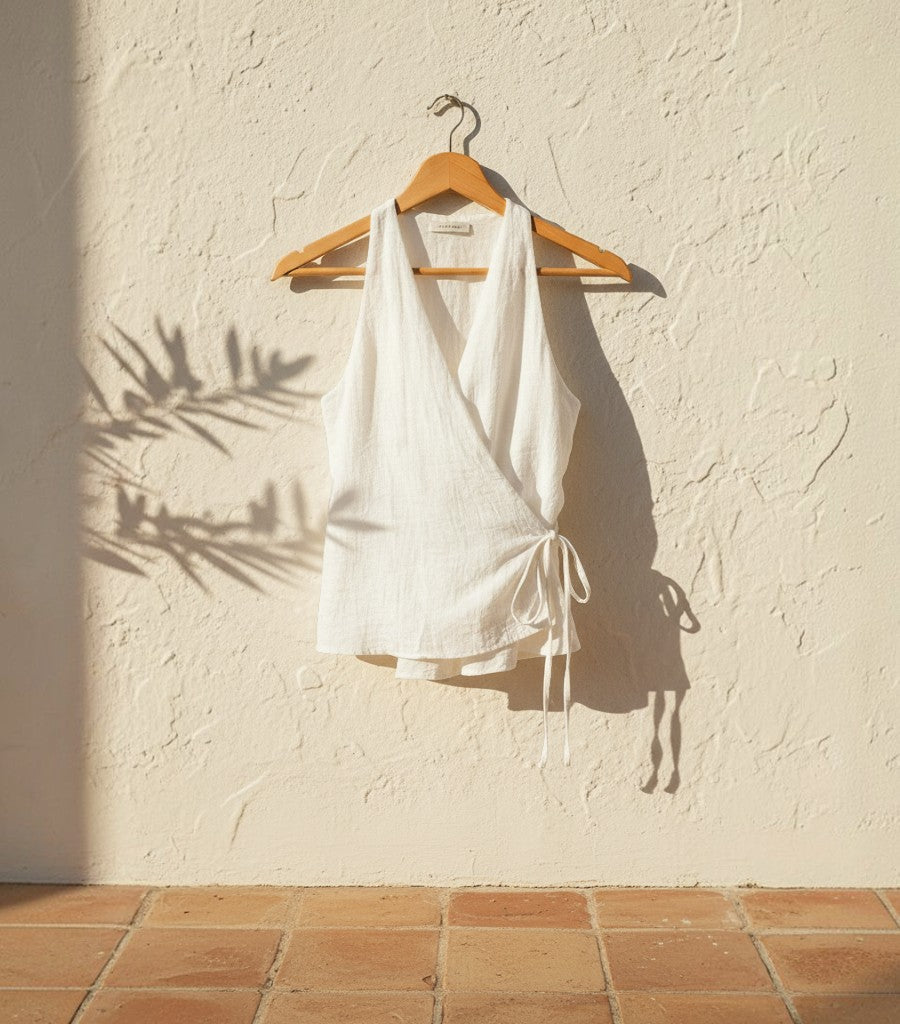 Top cruzado Clarvyna de lino blanco con escote en V y lazada lateral, ideal para un look fresco y elegante.