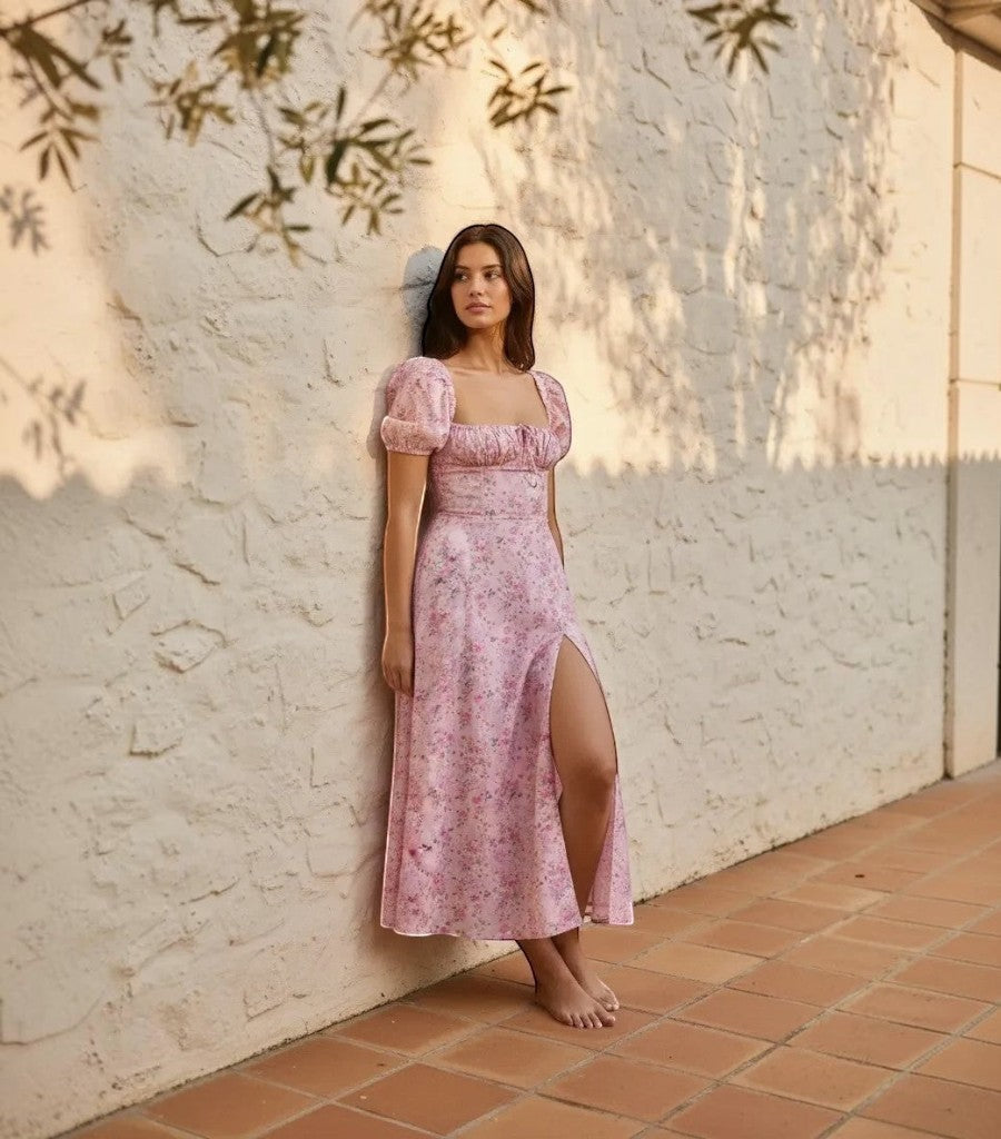 Modelo con vestido Clarvyna Amada rosa de flores, mangas abullonadas, escote cuadrado y abertura lateral en la pierna